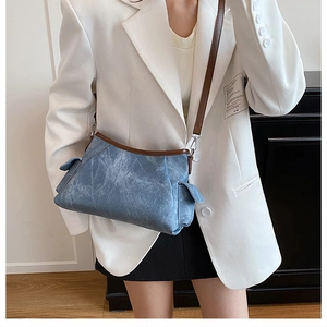 Blue denim texture shoulder bag with brown leather trim shown on a model in white suit