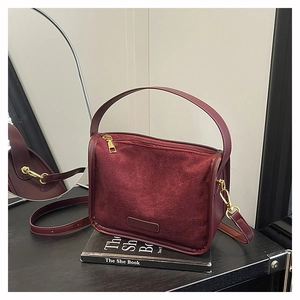 Détail du sac bandoulière en cuir bordeaux avec finitions dorées et texture mate