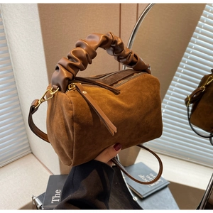 Détail du sac polochon en daim marron avec poignée nuage froncée et accents dorés