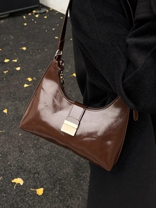 Retro dark brown patent leather hobo bag with gold buckle on a stylish autumn background