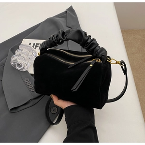 Détail du sac polochon en daim noir avec poignée en cuir froncé et fermetures dorées