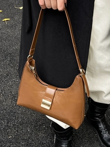 Brown semi-moon shoulder bag with golden buckle and chain on model in street setting
