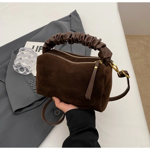 Détail du sac oreiller en daim marron foncé avec poignée plissée et garnitures dorées