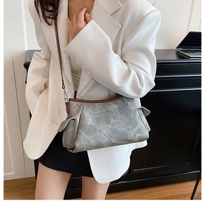 Detail of grey vintage textured crossbody bag featuring side pockets and brown shoulder straps