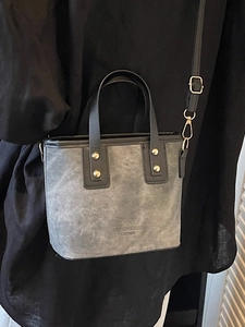 Gray matte mini tote bag with black leather handles and gold studs for everyday casual wear