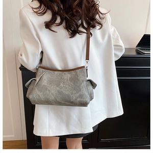 Detail view of the vintage gray shoulder bag with brown leather trim on a model