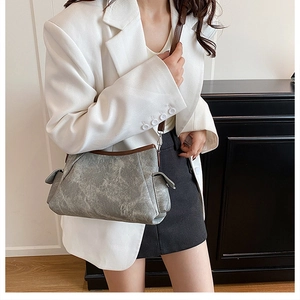 Detail of grey vintage textured shoulder bag with brown leather straps and side flap pocket