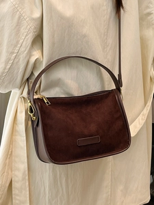 Sac bandoulière en suédine marron avec ferrures dorées porté par un mannequin