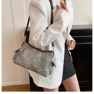 Detail of grey washed shoulder bag with brown leather trim worn with a white blazer