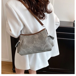 Detail view of the distressed grey canvas texture and brown leather strap on shoulder bag