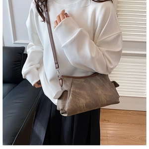 Detailed view of the vintage textured shoulder bag with brown leather trim and side pocket
