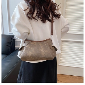Detail view of the brown textured crossbody bag with side flap pocket and dark strap