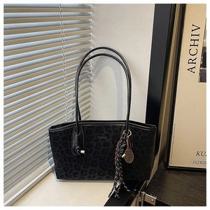 Gros plan détaillé d'un sac cabas noir à motif léopard avec un pendentif doré
