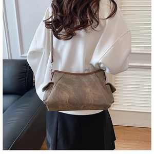 Detail of vintage brown crossbody bag featuring side pockets and textured matte finish