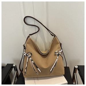 Detail of khaki hobo tote bag with leopard bow charms and leather strap on chair