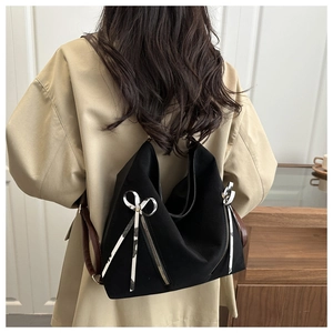 Detail of black large capacity tote bag with silver bow zippers and brown leather strap