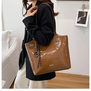 Macro detail of glossy dark brown tote bag showing smooth faux leather and fashion print