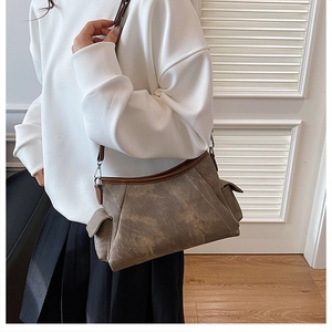 Close-up of vintage textured shoulder bag featuring side pockets and adjustable strap