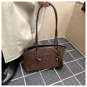 Détail du sac cabas léopard avec badge Fashion en métal et pendentif en corde