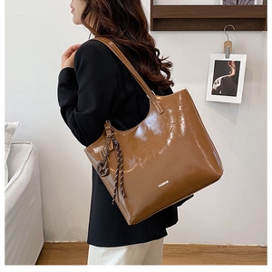 Detail of caramel brown glossy shoulder bag featuring delicate straps and side rope charm