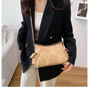 Close-up of vintage leather texture and side flap pocket details on khaki shoulder bag