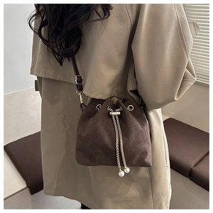 Détail du sac seau marron foncé mat avec cordon perlé et bandoulière dorée