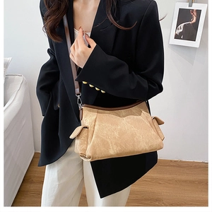 Detail of light brown crossbody bag with unique wrinkled texture and dark shoulder strap