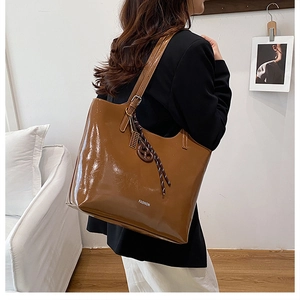 Detailed view of brown glossy tote bag with fashion lettering and decorative knots