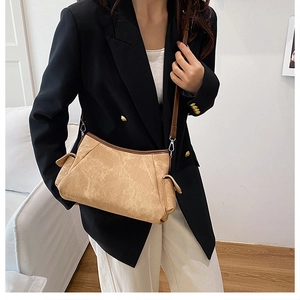 Detail of khaki vintage textured crossbody bag with side pocket and brown shoulder strap