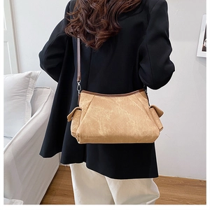 Detail view of khaki shoulder bag with side flap pockets on a model from the back