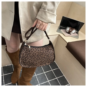 Macro detail of leopard print shoulder bag featuring crescent shape and gold zipper