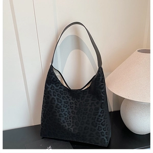 Close-up of leopard print hobo bag texture showing black shoulder strap and large capacity
