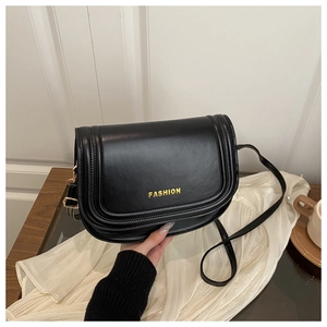 Detailed view of black leather saddle bag featuring gold metal FASHION lettering logo