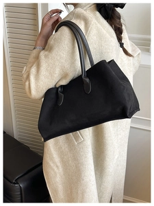 Large black suede tote bag shown on model with beige coat for daily commuter style