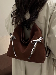 Fashionable dark coffee suede tote bag with ribbon bows shown on a model's shoulder