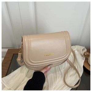 Detail showing beige saddle bag with golden FASHION logo and high quality PU leather texture