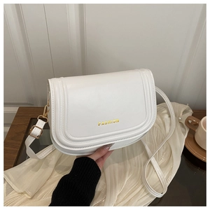 Detailed view of white PU leather flap bag with gold FASHION lettering and metal hardware