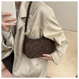 Close-up of leopard print crescent bag on model in a minimalist stylish indoor setting