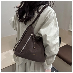 Détail du sac à bandoulière marron foncé mat avec pompon et boucle métallique élégante