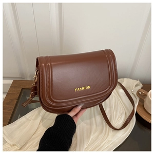 Detailed view of a vintage brown leather saddle bag with golden FASHION lettering