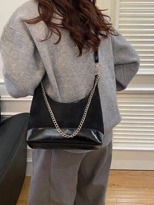 Elegante borsa sottobraccio nera con catena d'oro e finitura opaca su modella