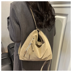 Détail du sac cabas kaki clair avec pompon à franges sur un manteau d'hiver gris