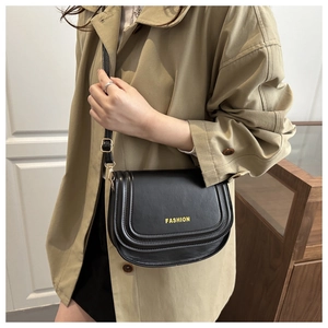 Detail of fashion crossbody bag with gold buckle and adjustable strap on a trench coat