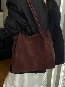 Retro burgundy suede tote bag with woven shoulder straps worn by a female model