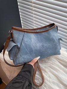 Light blue denim shoulder bag with brown leather trim and side pockets, casual style