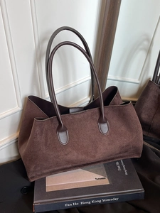 Large dark brown suede tote bag for women placed on an art book in a minimalist room