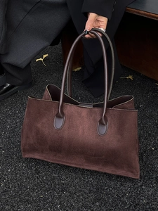 Minimalist large brown suede tote bag with leather handles on autumn leaves background