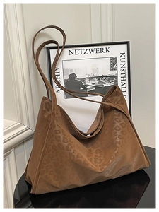 Detail of dark brown leopard print tote bag with matte texture on a mirrored surface