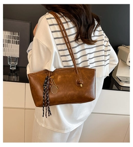 Close-up of brown PU leather tote bag with vintage texture and tennis racket charm
