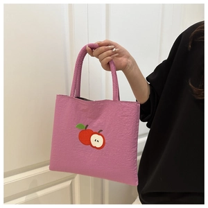 Close-up of pink nylon mini tote bag featuring detailed apple embroidery and pleated handles